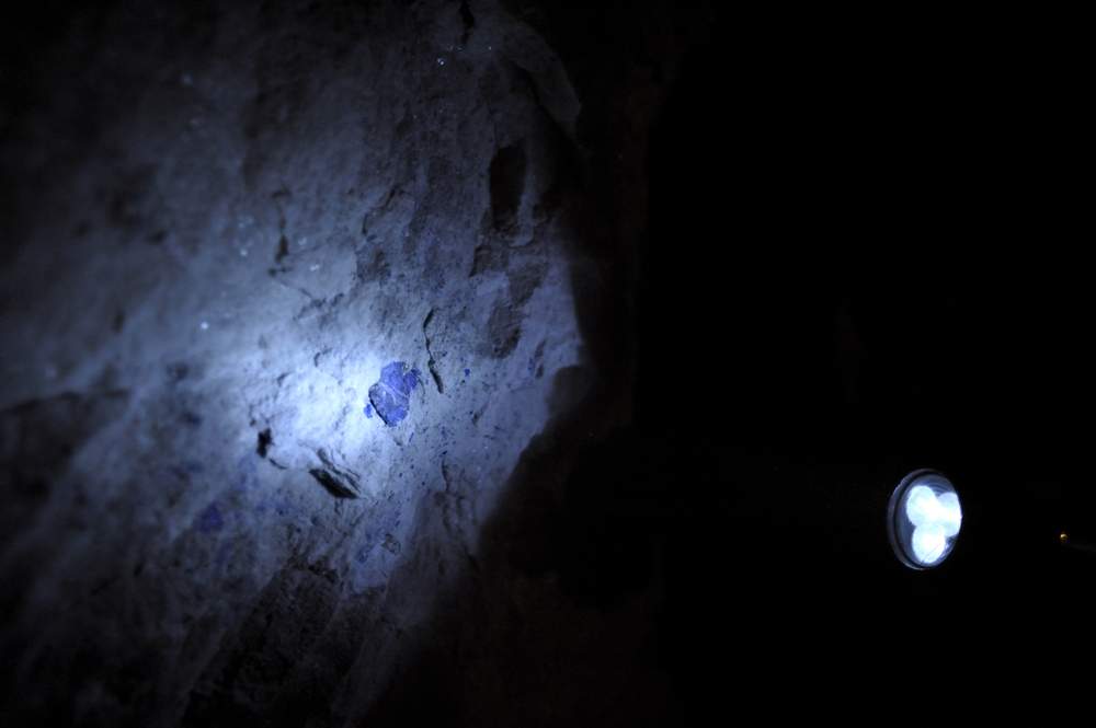 A miner with a flashlight illuminates the rock to find deposits of lapis lazuli. The lapis lazuli is mostly found in marble. Credit: Philip Poupin
